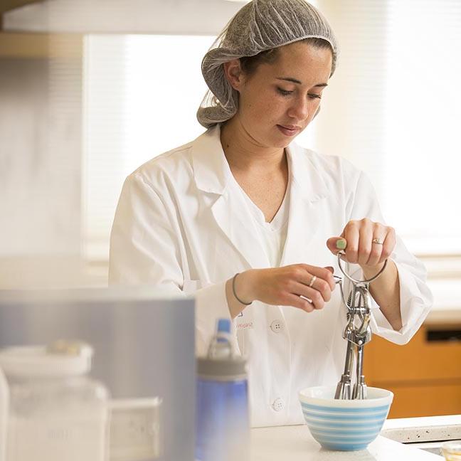 A student works with a beater in a food lab